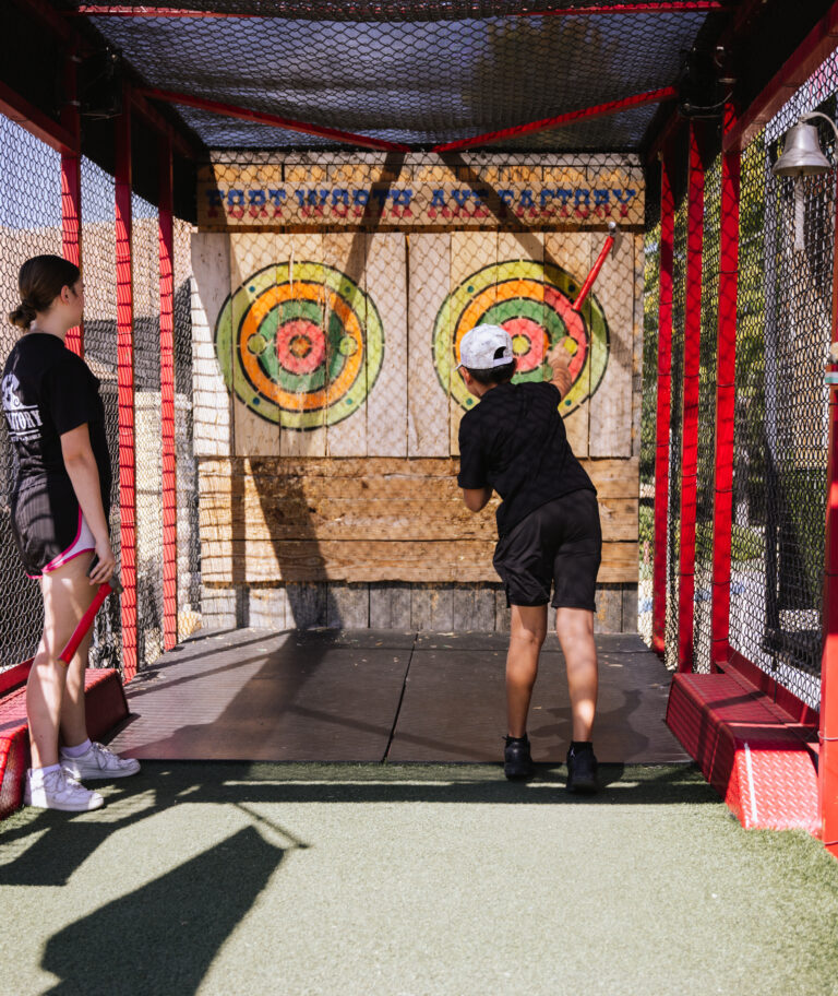 A boy throws an axe toward a wooden target