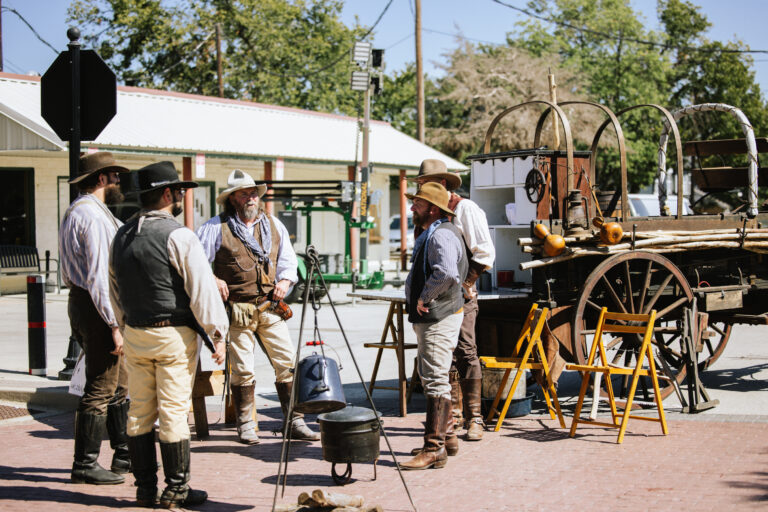 A group of men dressed in cowboy attire stands in a circle