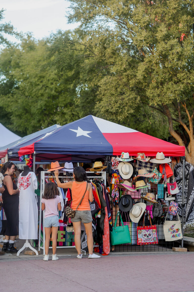 A woman and a child are browsing merchandise at a market tent