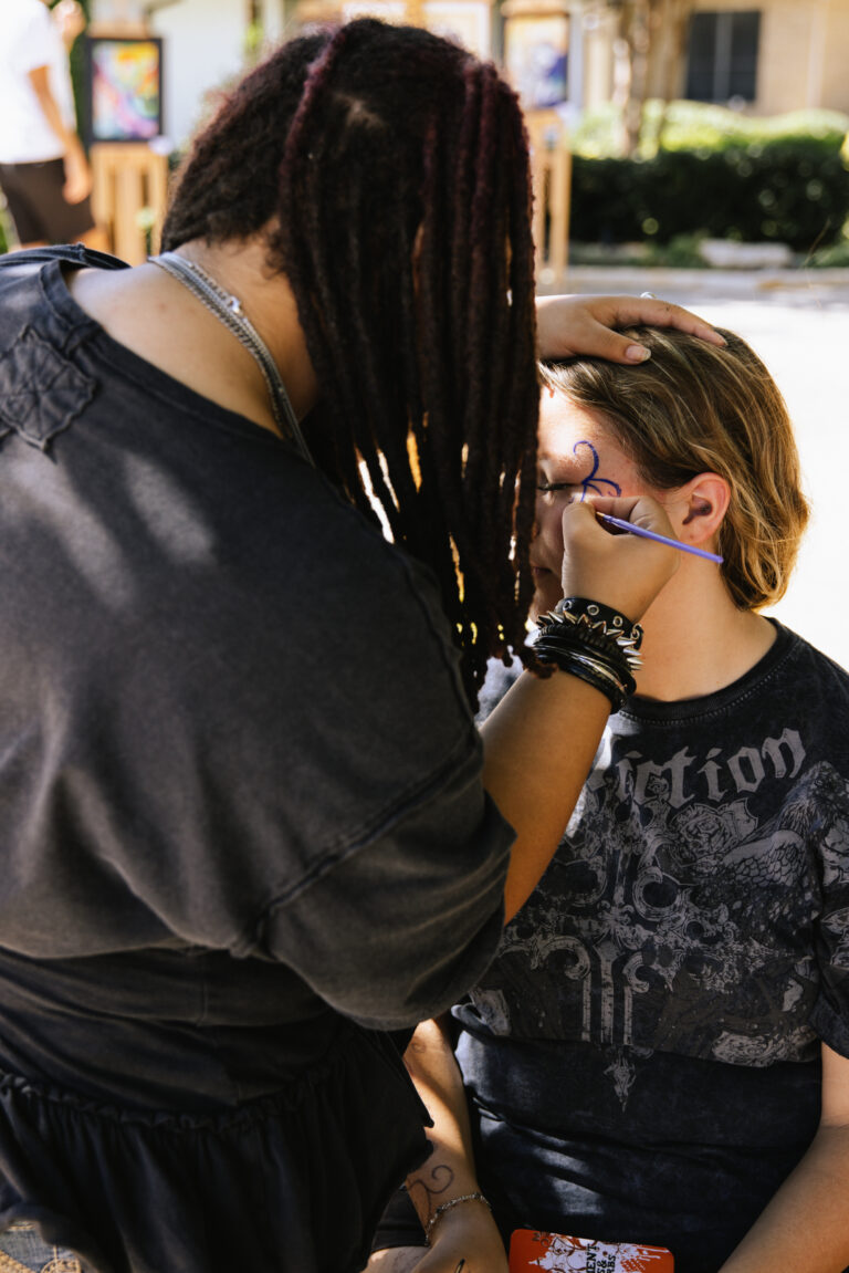 A woman painting the face of another woman